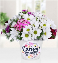 Anneler günü temalı seramik vazo içerisinde beyaz papatya, hüsnüyusuf ve yeşillikler ile hazırlanmıştır.